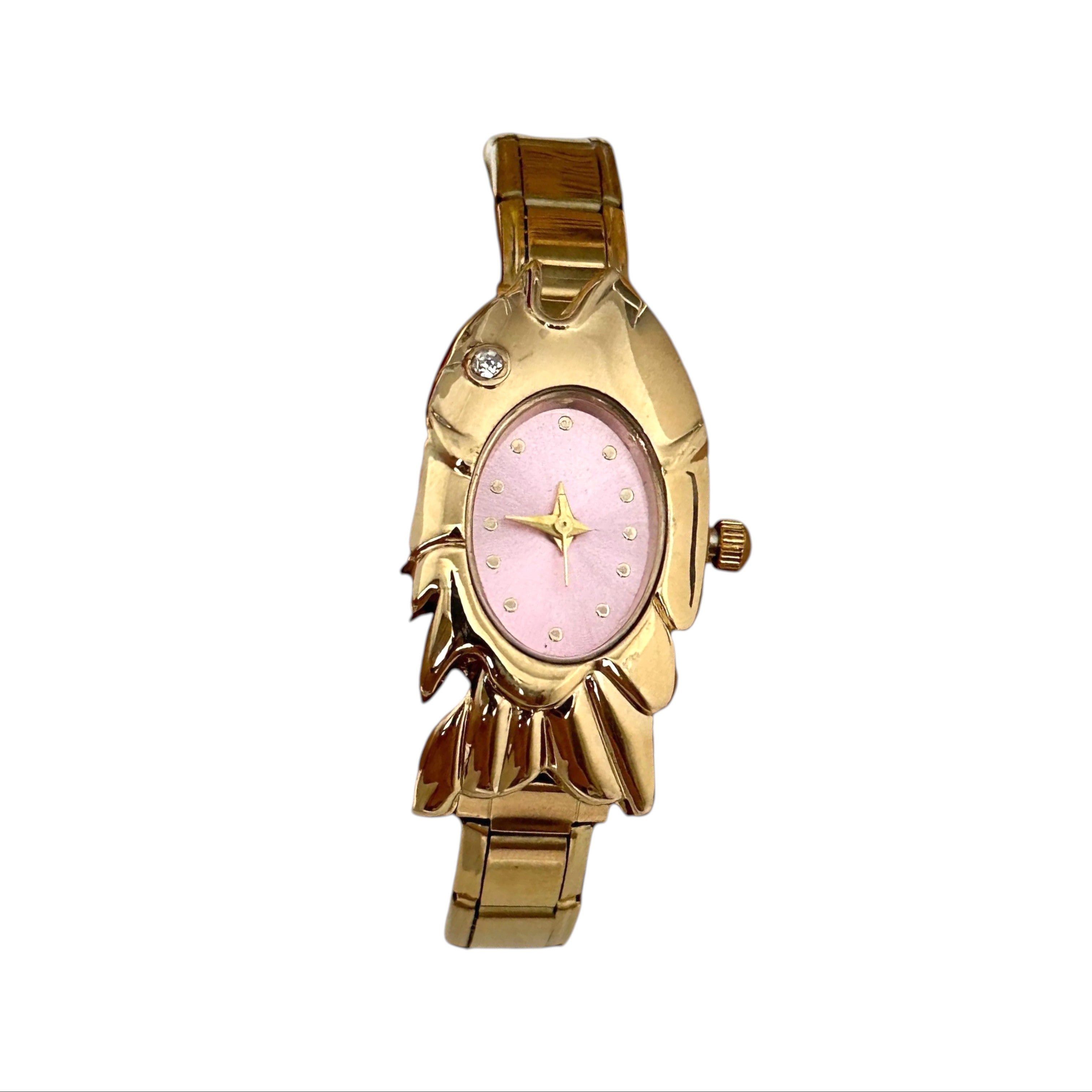 CP STATEMENT gold-tone stainless steel fish-shaped quartz watch with a pink dial and Roman numeral markers.