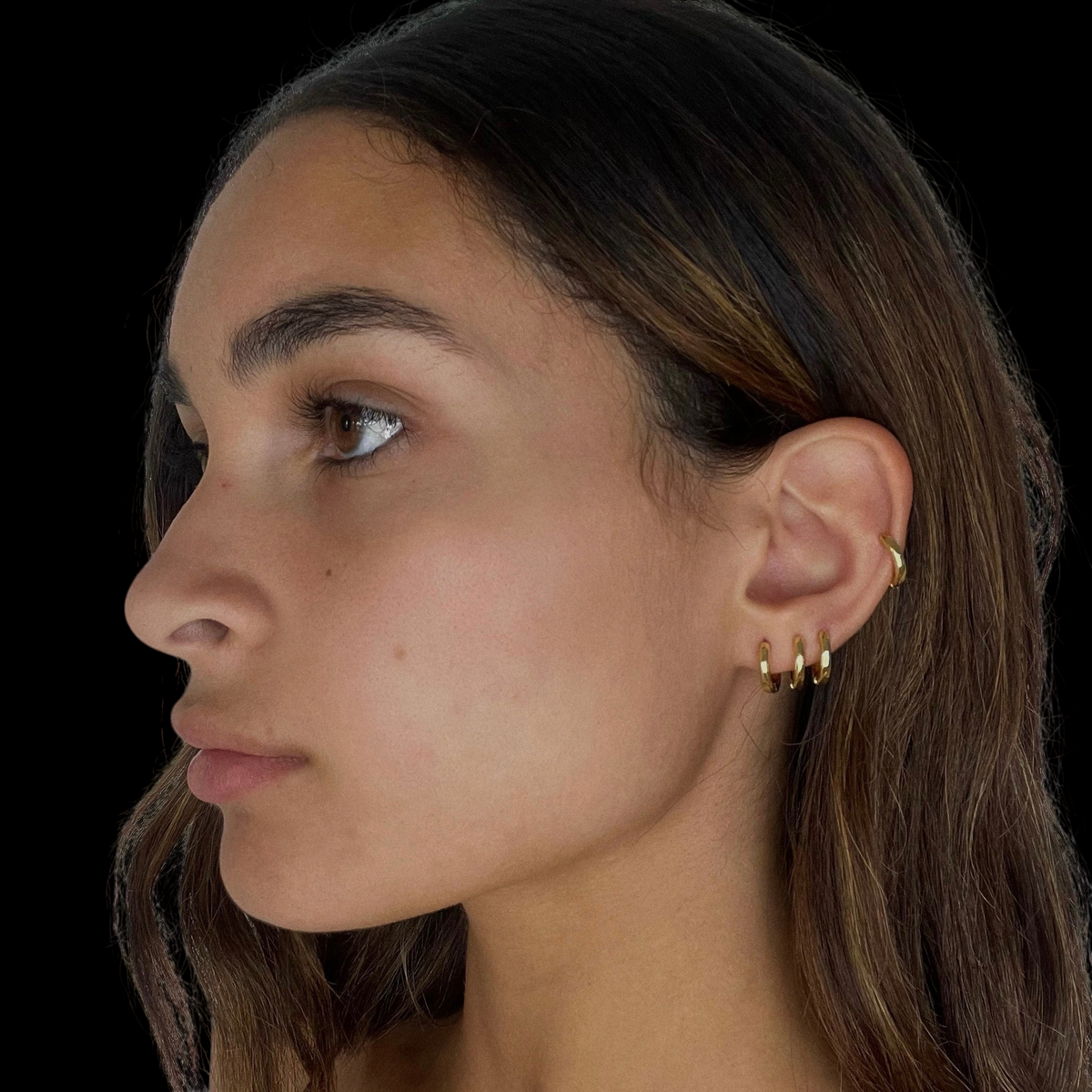 CP STATEMENT 18k gold plated 14mm Classica huggie earrings worn by a model in a side profile view